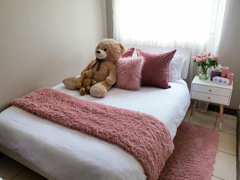 A cozy bedroom featuring neutral wall tones, tiled flooring, and soft window treatments, providing a comfortable and well-maintained sleeping space.