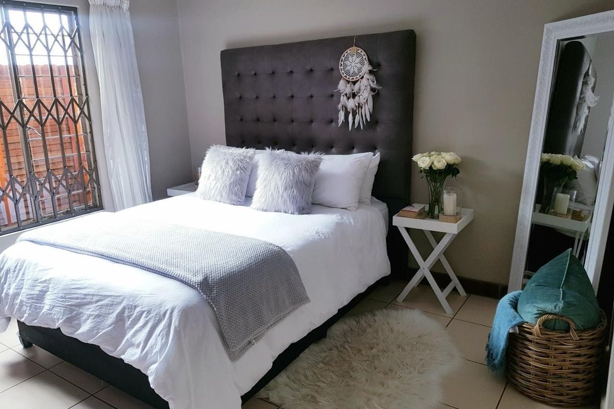 A well-maintained bedroom featuring tiled flooring and a window fitted with a security gate.