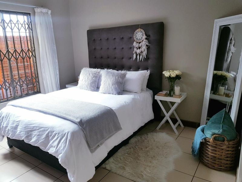 A well-maintained bedroom featuring tiled flooring and a window fitted with a security gate.
