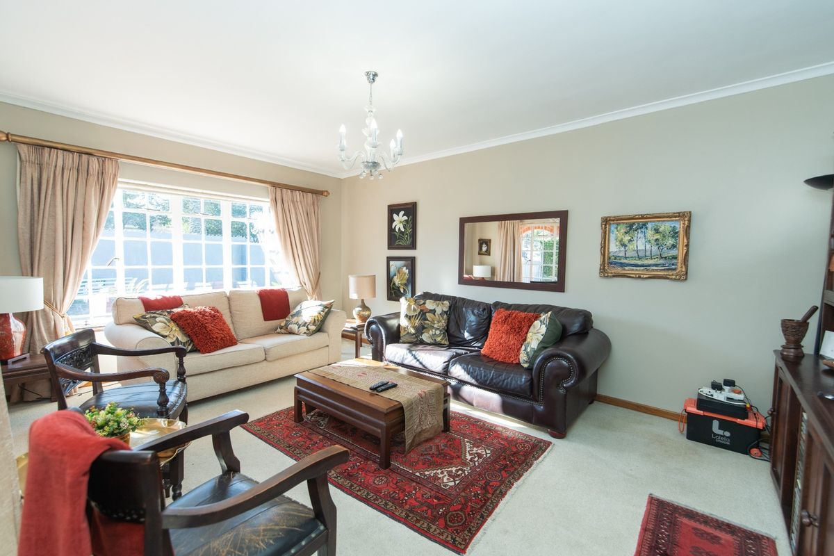 A comfortable living room featuring a large window, neutral wall tones, and classic cove cornicing, providing a bright and inviting space.