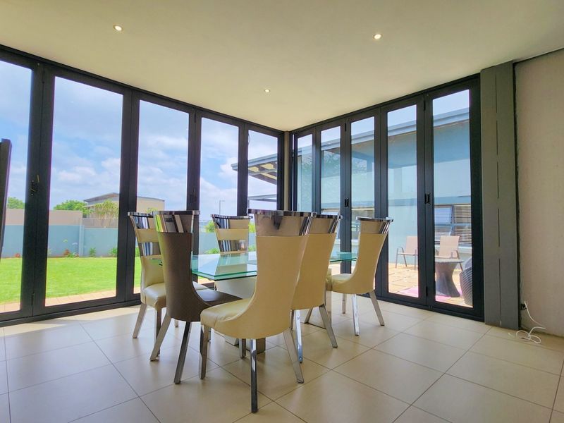 Bright dining area featuring large aluminium stacker doors that provide seamless indoor-outdoor flow and abundant natural light.