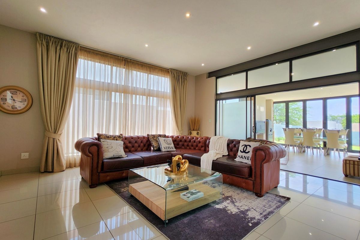 Spacious living room featuring large format floor tiles, recessed lighting, and expansive sliding glass doors that provide seamless access to the outdoor area.