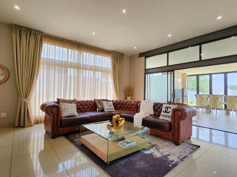 Spacious living room featuring large format floor tiles, recessed lighting, and expansive sliding glass doors that provide seamless access to the outdoor area.