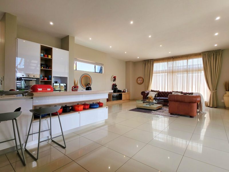 Spacious open-plan living area featuring a modern kitchen with built-in cabinetry, a central island, and seamless flow to the lounge with large sliding doors.