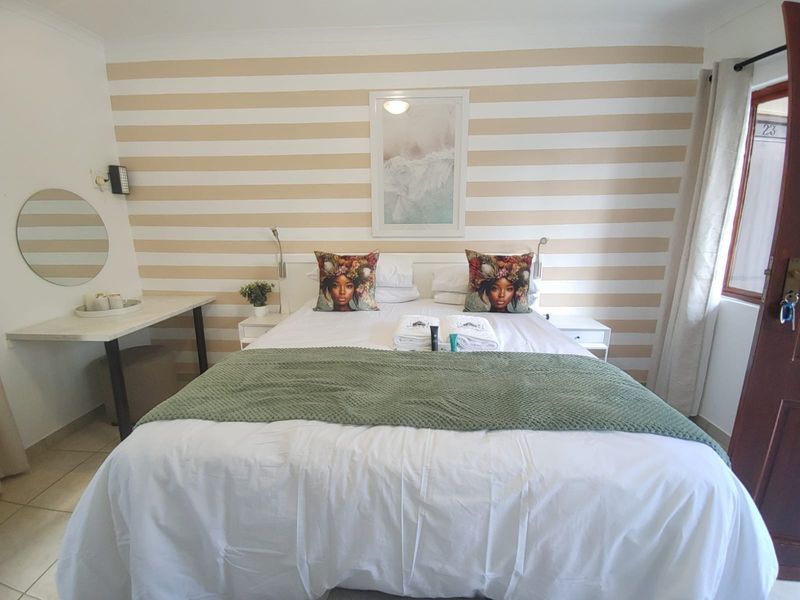 A well-lit bedroom featuring tiled flooring, a built-in vanity area, and a decorative striped feature wall.