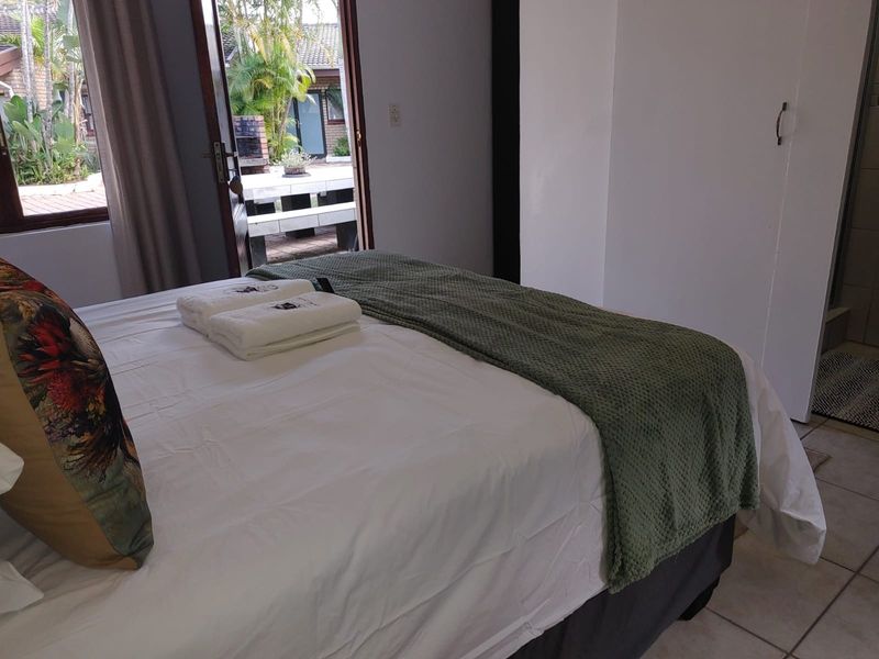 A bedroom featuring tiled flooring, a built-in wardrobe, and a sliding door providing direct access to an outdoor patio area.