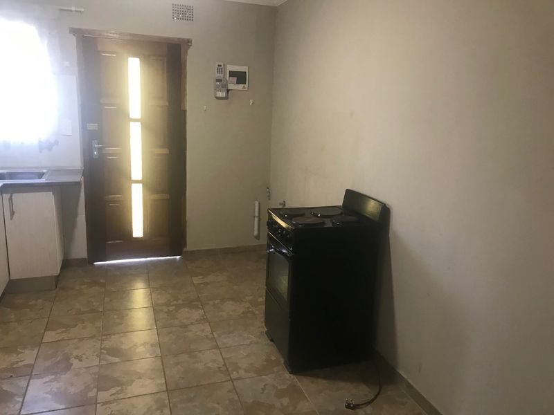 A functional kitchen area featuring tiled flooring, built-in cabinetry with a sink, and a freestanding electric stove, providing a basic foundation for renovation.