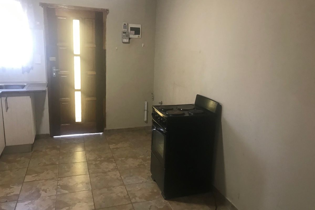 A functional kitchen area featuring tiled flooring, built-in cabinetry with a sink, and a freestanding electric stove, providing a basic foundation for renovation.