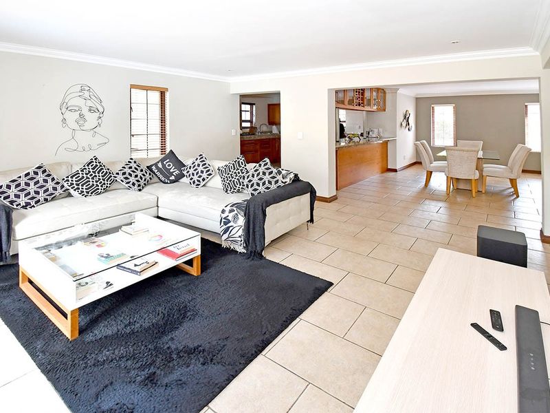 Spacious open-plan living and dining area featuring neutral tiled flooring, crown molding, and a functional kitchen with granite countertops and a breakfast bar.
