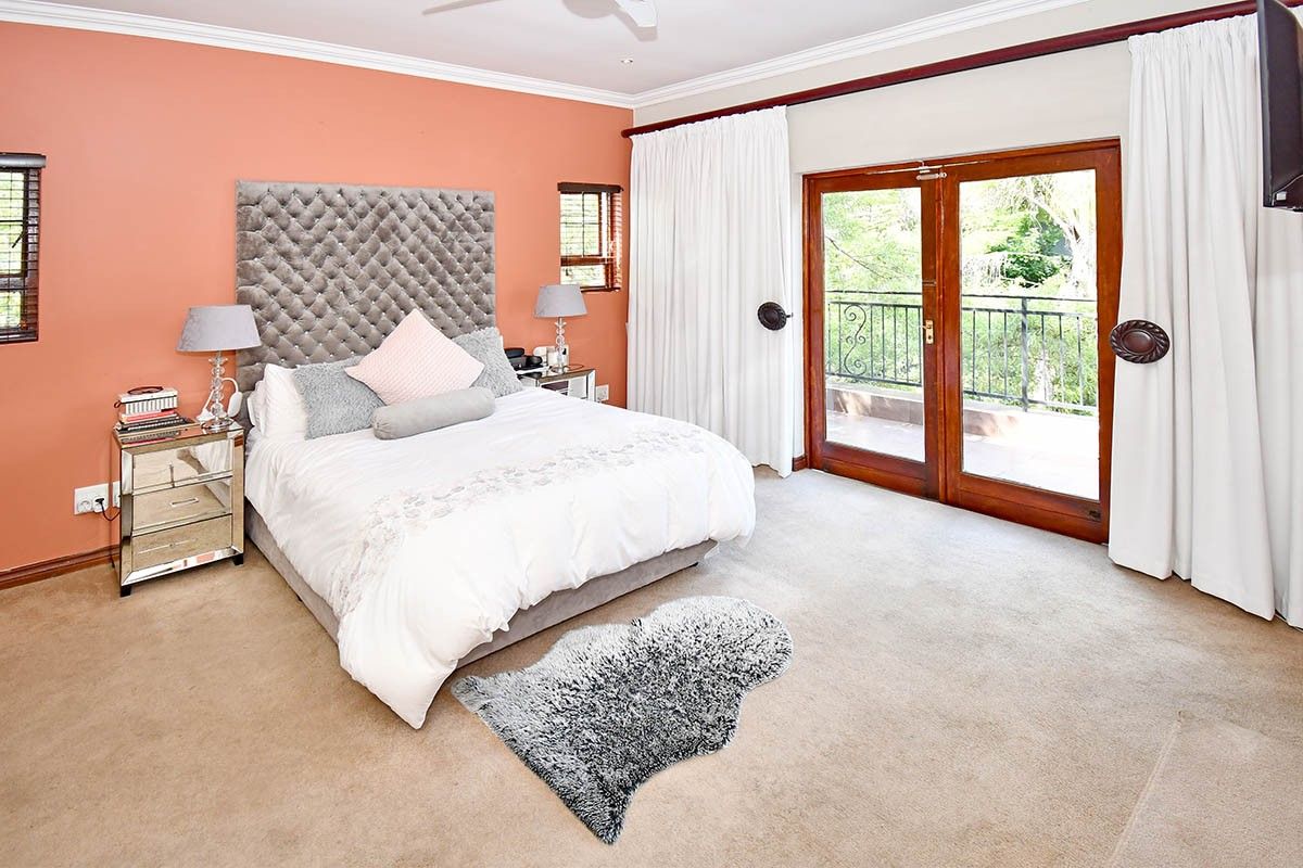 Spacious bedroom featuring carpeted flooring, crown molding, and double glass doors providing direct access to a private balcony.