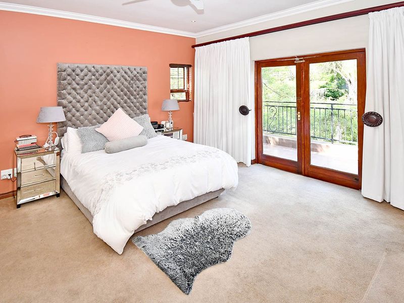 Spacious bedroom featuring carpeted flooring, crown molding, and double glass doors providing direct access to a private balcony.