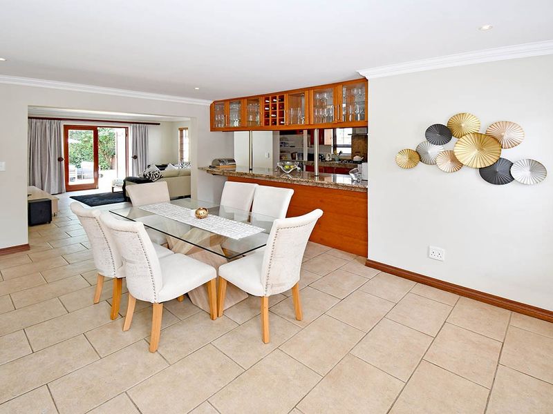 Open-plan dining area featuring tiled floors and a breakfast bar with granite countertops, seamlessly connecting to the kitchen and outdoor patio space.