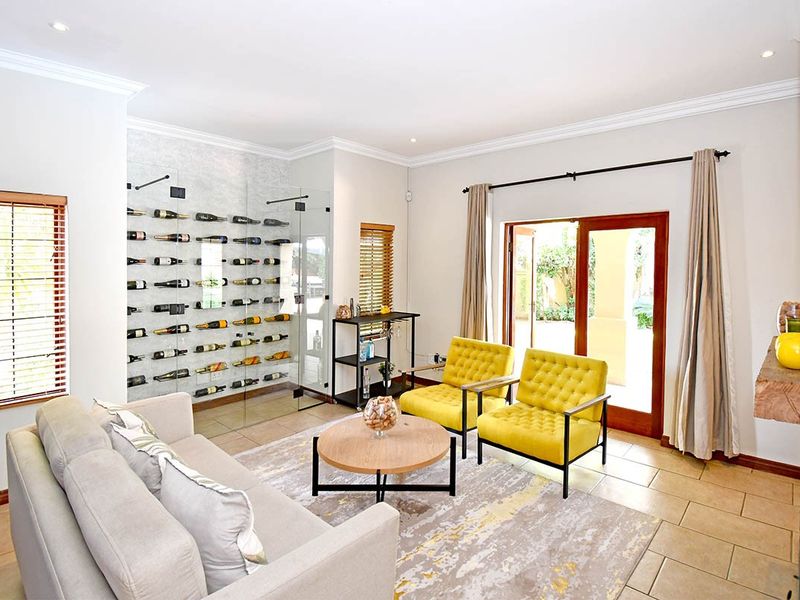 Spacious living area featuring a modern glass-enclosed wine cellar, tiled flooring, and direct access to the outdoor patio through sliding glass doors.