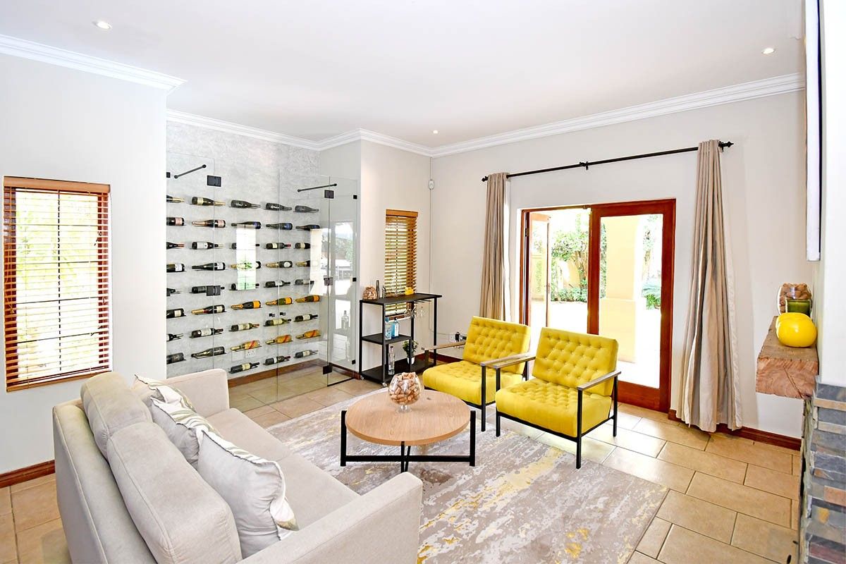 Spacious living area featuring a modern glass-enclosed wine cellar, tiled flooring, and direct access to the outdoor patio through sliding glass doors.