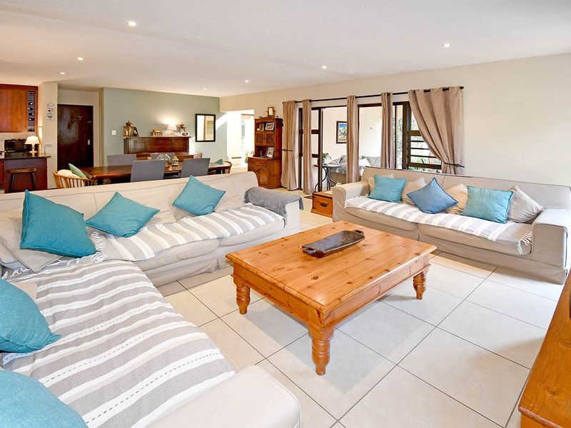 Spacious open-plan living and dining area featuring tiled floors, recessed lighting, and seamless flow to an outdoor patio through sliding glass doors.