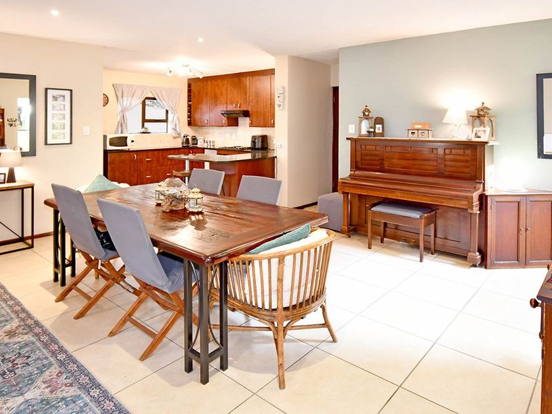 Open-plan dining and kitchen area featuring tiled flooring, wooden cabinetry, and a central kitchen island, creating a functional and connected living space.