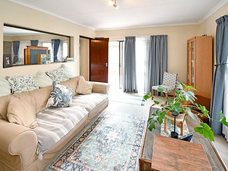 A comfortable living room featuring a built-in interior window, coved ceilings, and direct access to the outdoor area through a sliding glass door.