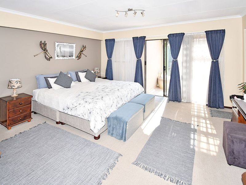 Spacious bedroom featuring neutral wall tones, carpeted flooring, and a sliding glass door providing direct access to an outdoor patio area.