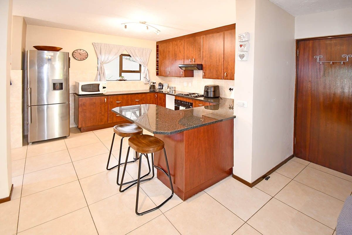 A functional kitchen featuring wooden cabinetry, granite countertops, a breakfast bar, and built-in cooking appliances with tiled flooring throughout.