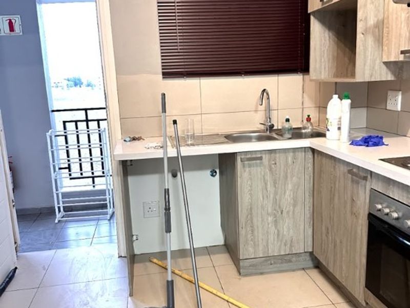 A functional kitchen featuring wood-look cabinetry, tiled flooring, and a built-in oven, with direct access to an outdoor balcony area.