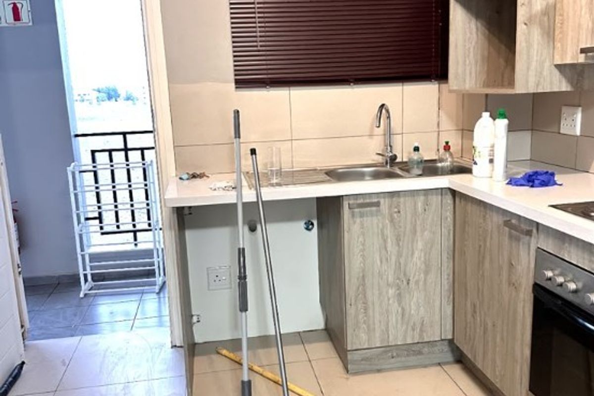 A functional kitchen featuring wood-look cabinetry, tiled flooring, and a built-in oven, with direct access to an outdoor balcony area.