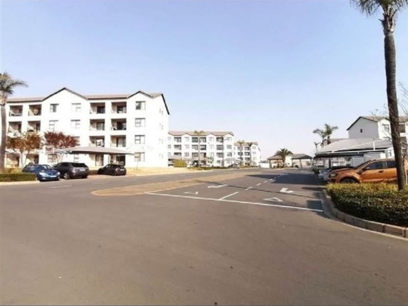 A view of the residential complex street, featuring paved roads, designated parking areas, and carports within a well-maintained estate setting.