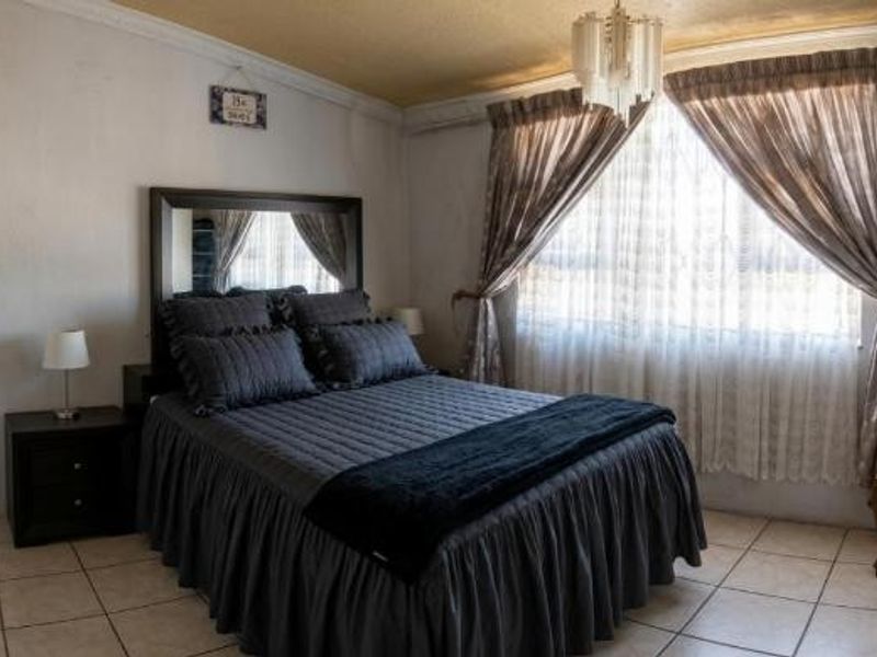 A functional bedroom featuring tiled flooring, a built-in wardrobe, and classic ceiling cornice detailing, offering a comfortable and well-maintained living space.