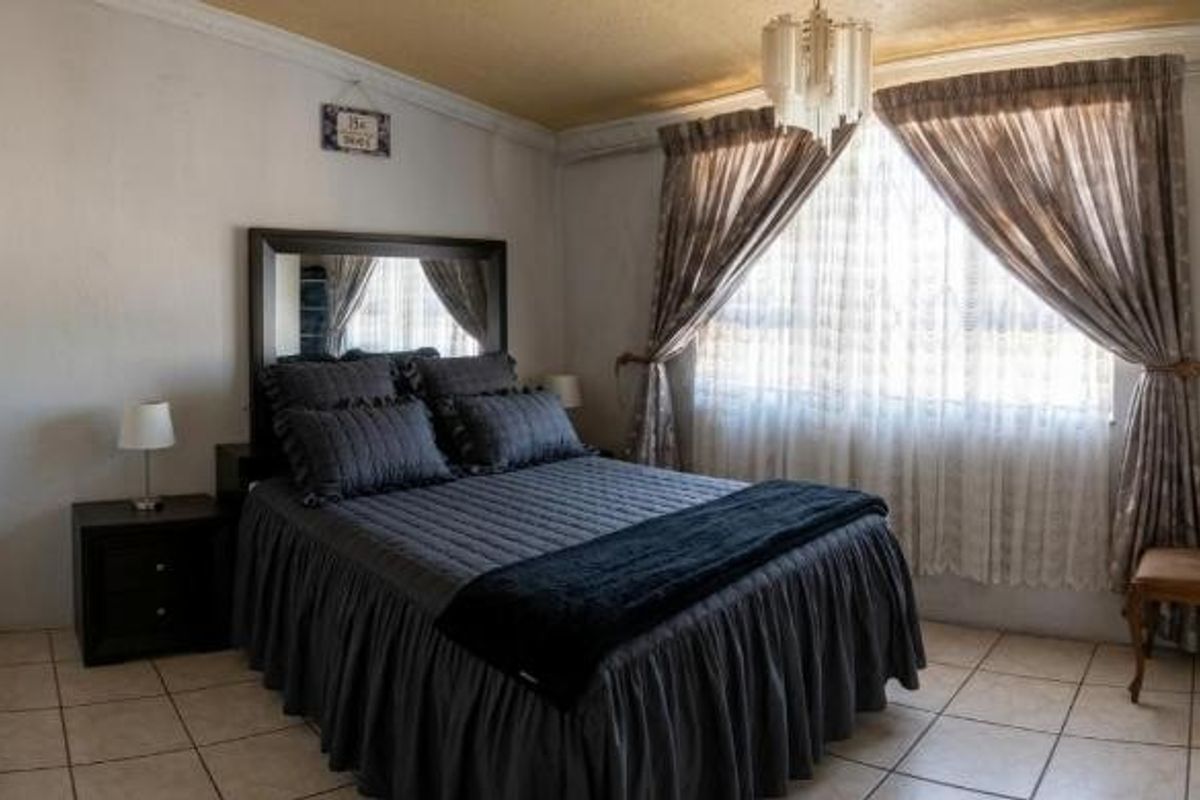 A functional bedroom featuring tiled flooring, a built-in wardrobe, and classic ceiling cornice detailing, offering a comfortable and well-maintained living space.
