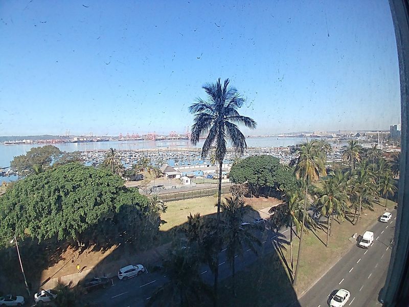 Elevated view overlooking the marina, harbor, and surrounding coastal landscape from an apartment window.