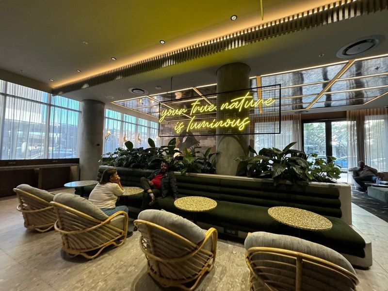 Modern clubhouse lounge area featuring contemporary built-in banquette seating, ambient cove lighting, and expansive floor-to-ceiling windows with a sophisticated interior design.