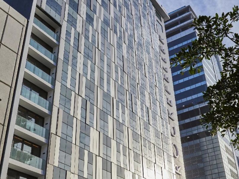 A modern high-rise apartment building featuring a contemporary glass and panel facade with integrated balconies.