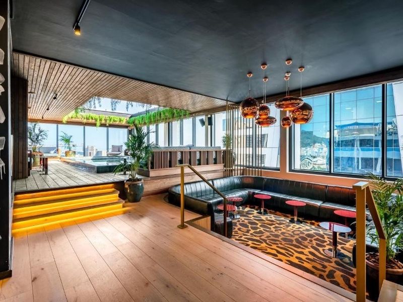 Sophisticated open-plan living area featuring a sunken lounge, timber flooring, raised pool deck, and expansive floor-to-ceiling windows with modern architectural finishes.