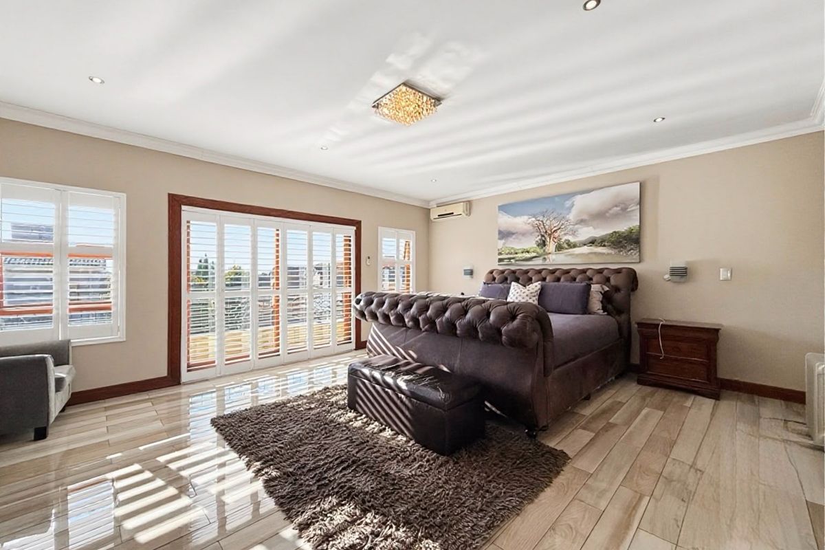 Spacious bedroom featuring tiled flooring, recessed lighting, and large sliding glass doors with plantation shutters, providing ample natural light and access to the outdoors.