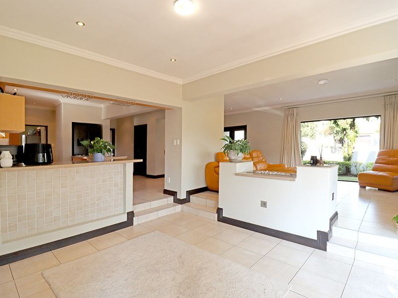 Spacious open-plan living area featuring tiled floors, recessed lighting, and a functional kitchen breakfast bar with direct access to the outdoor patio.