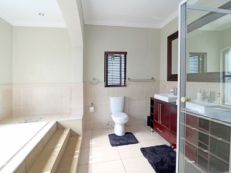 A well-maintained bathroom featuring a built-in bathtub with tiled surround, a modern vanity with basin, and a separate shower enclosure.