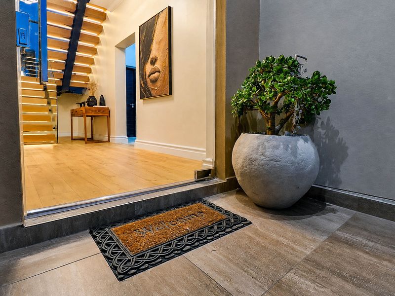 Modern entrance featuring a striking floating staircase with integrated lighting, glass balustrades, and high-quality timber flooring leading into the home.
