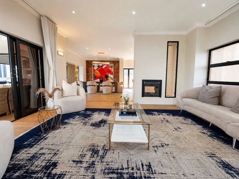 Spacious open-plan living and dining area featuring hardwood floors, a modern built-in fireplace, exposed brick accents, and large sliding doors leading to the patio.