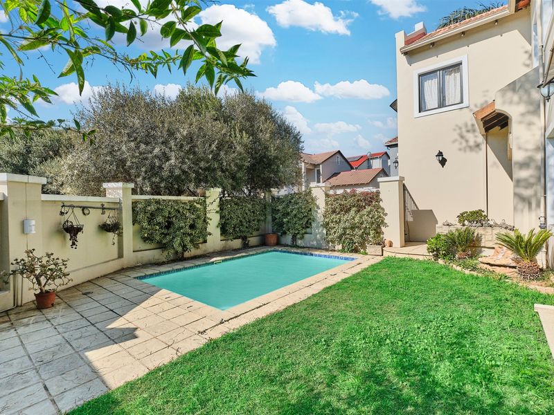 A private backyard featuring a swimming pool, paved patio area, and established garden borders adjacent to the main house structure.