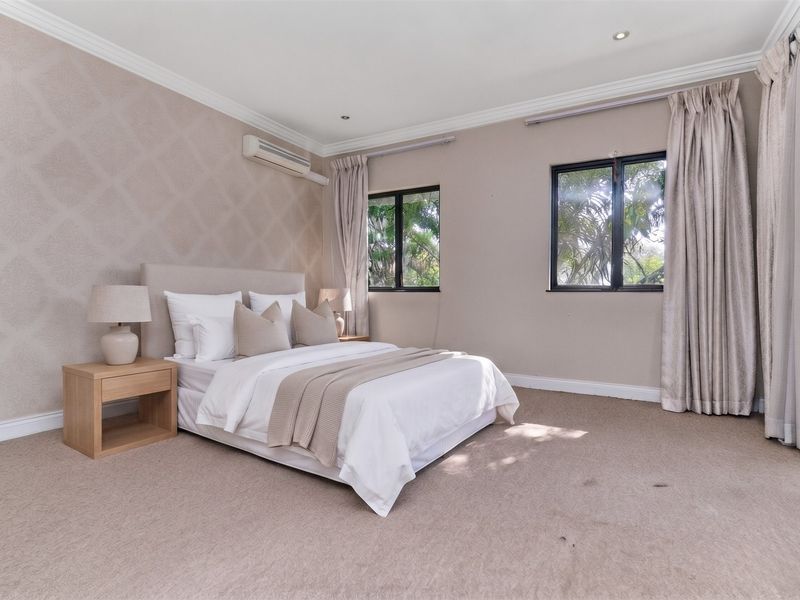 Spacious bedroom featuring neutral wall finishes, carpeted flooring, crown molding, and an integrated air conditioning unit with large windows providing natural light.