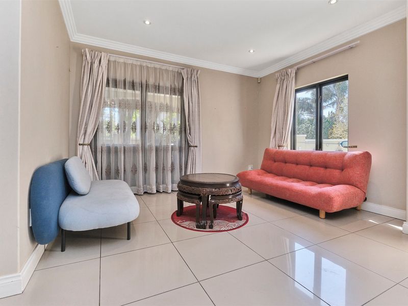 A bright living room featuring large format floor tiles, recessed downlighting, and sliding glass doors providing natural light and garden access.