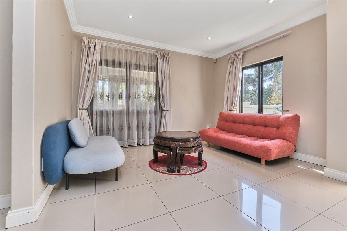 A bright living room featuring large format floor tiles, recessed downlighting, and sliding glass doors providing natural light and garden access.