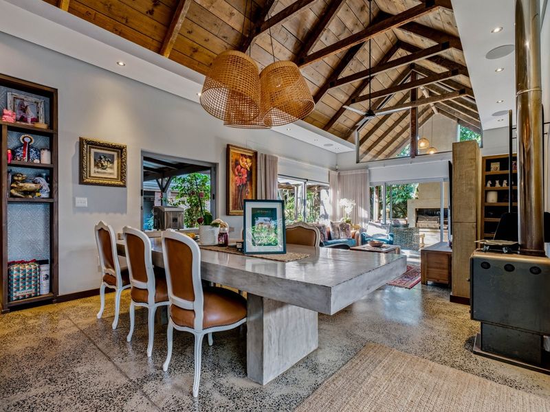 Spacious open-plan living and dining area featuring a dramatic vaulted timber ceiling, polished concrete floors, and a modern wood-burning fireplace.
