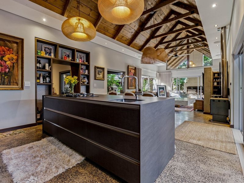 Spacious open-plan living area featuring a modern kitchen island, polished concrete floors, and a striking vaulted ceiling with exposed timber trusses.