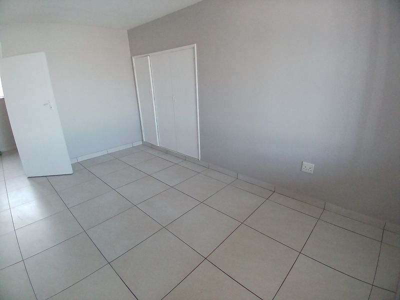 A clean, empty bedroom featuring neutral tiled flooring and built-in storage cupboards, providing a blank canvas for personalization.