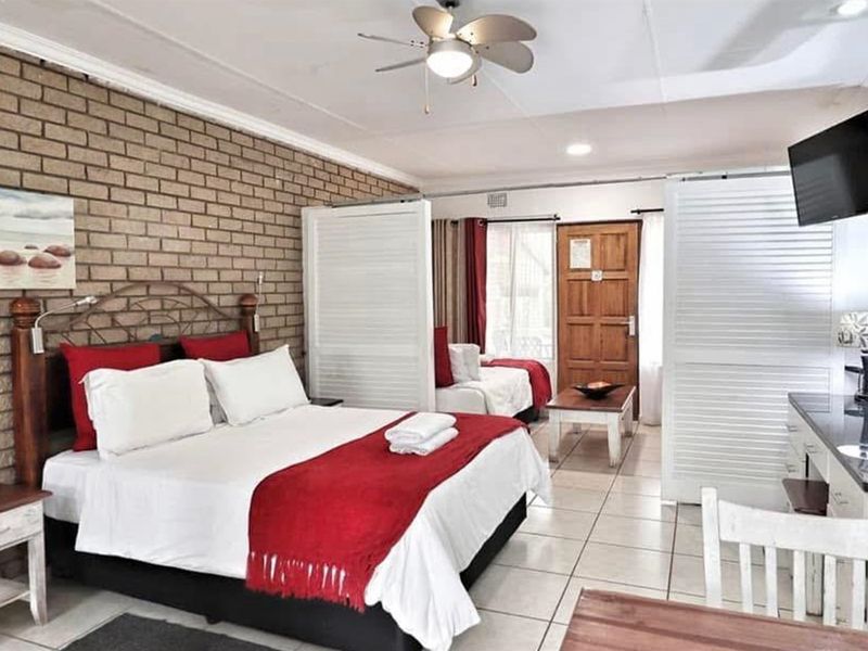 Spacious bedroom featuring an exposed brick feature wall, tiled flooring, and a ceiling fan, with a functional layout and integrated room divider.