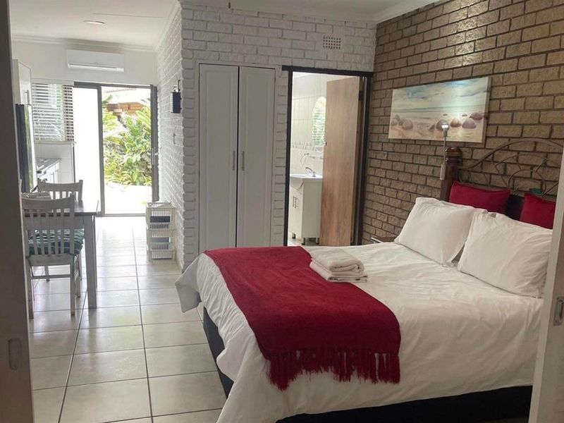 Bedroom featuring exposed brick walls, tiled flooring, built-in wardrobe, and direct access to an outdoor patio area.