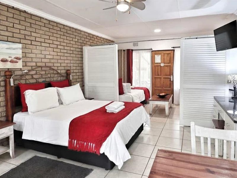 Spacious bedroom featuring an exposed brick feature wall, tiled flooring, and functional sliding room dividers for flexible living space.