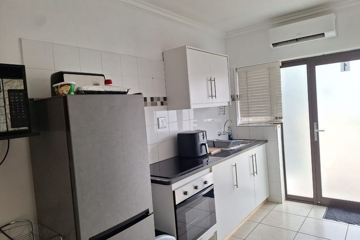 A functional kitchen featuring white cabinetry, tiled backsplash, built-in oven and hob, and direct access to an outdoor area.