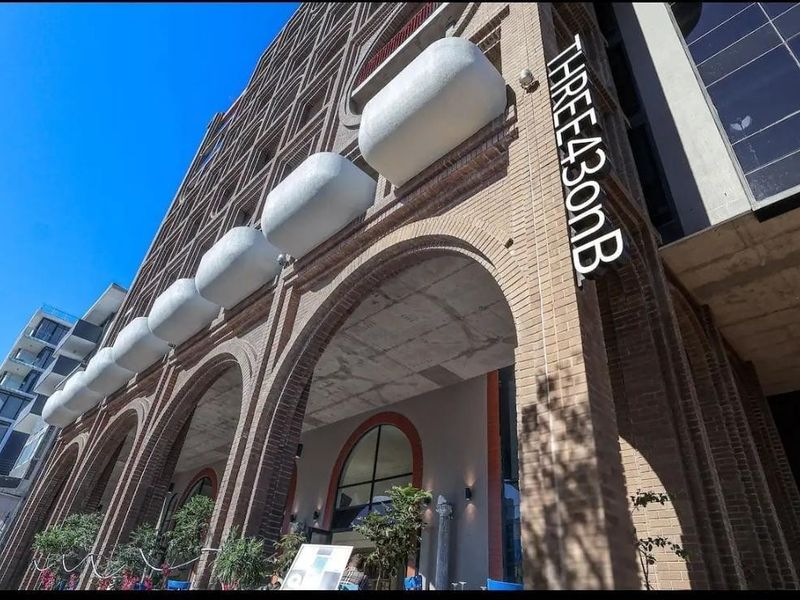 Low angle view of the modern brick facade featuring arched architectural details and prominent building signage at the entrance.