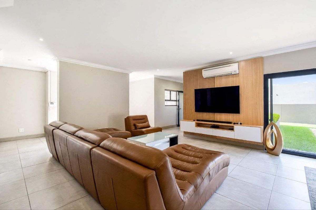 Modern living room featuring a timber slat feature wall, built-in media cabinetry, split-system air conditioning, and large sliding glass doors leading to the garden.